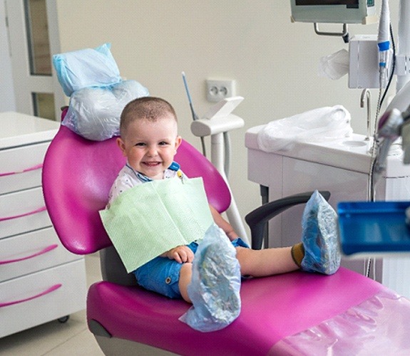 Father brushing young daughter’s teeth with dentist