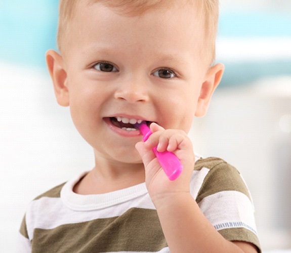 Little boy brushing teeth with pink toothbrush