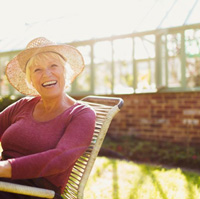 Older woman smiling in a chair outside 