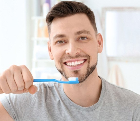 Man preventing dental emergencies by brushing his teeth in Aurora  
