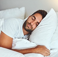 Man resting in bed with dental implants