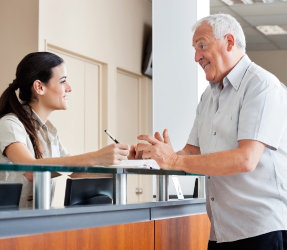 man speaking to front desk worker