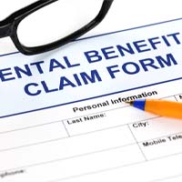 Dental benefits claim form with pen and glasses