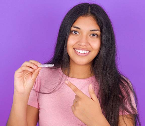 Teeth holding Invisalign Teen aligner in Aurora