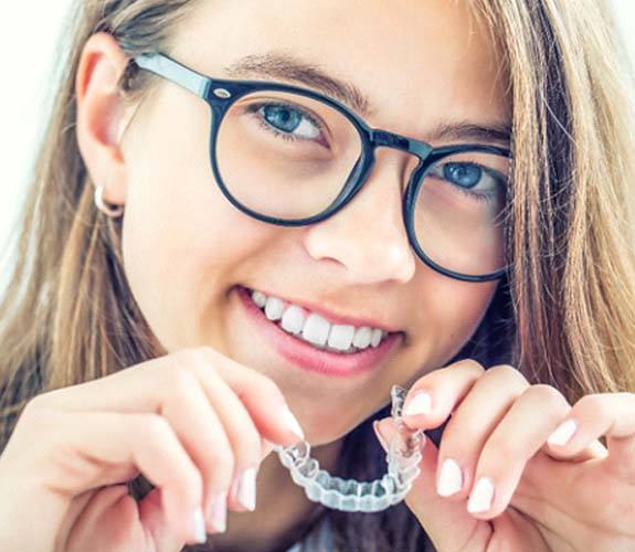 Girl inserting Invisalign Teen in Aurora