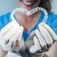 Dentist holding clear retainers in Aurora