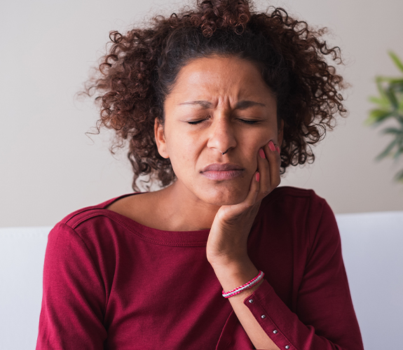 woman holding cheek in pain