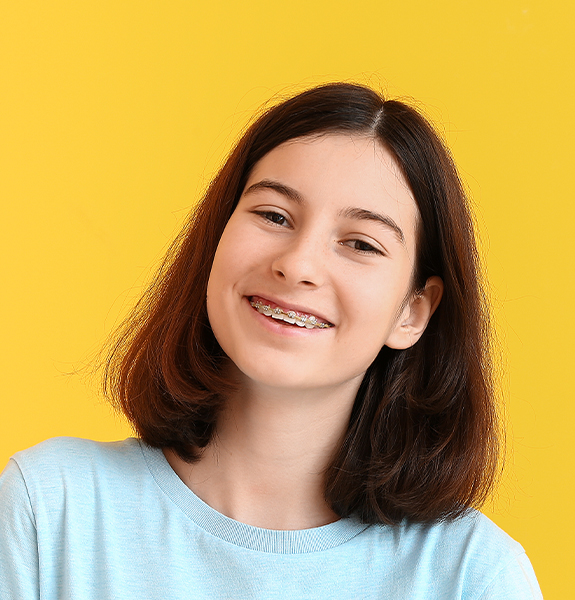girl with braces smiling with yellow background