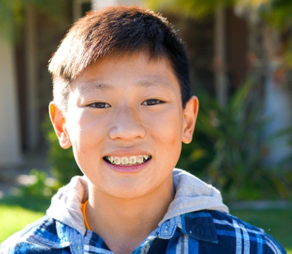 Young boy smiling with traditional metal braces in Aurora, IL