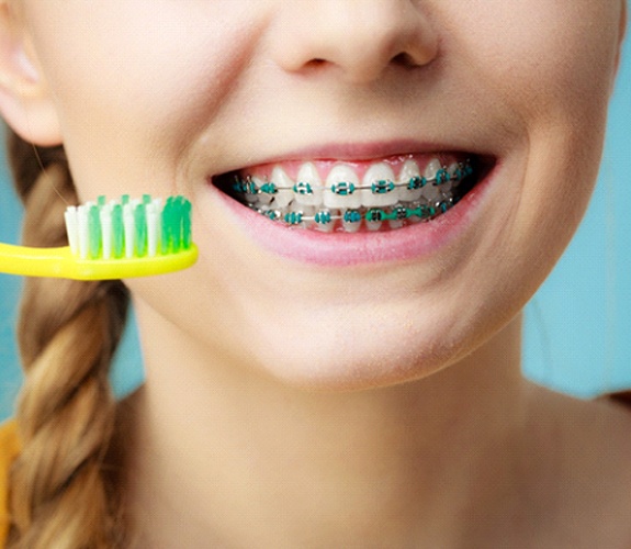 Young girl about to brush traditional metal braces in Aurora, IL