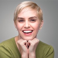 Young woman wearing a green shirt and smiling with veneers  