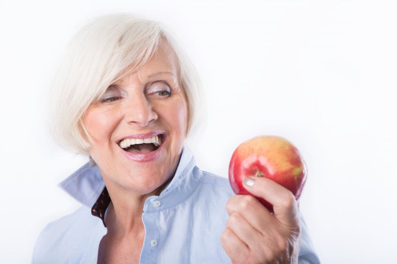 woman eating an apple with dentures