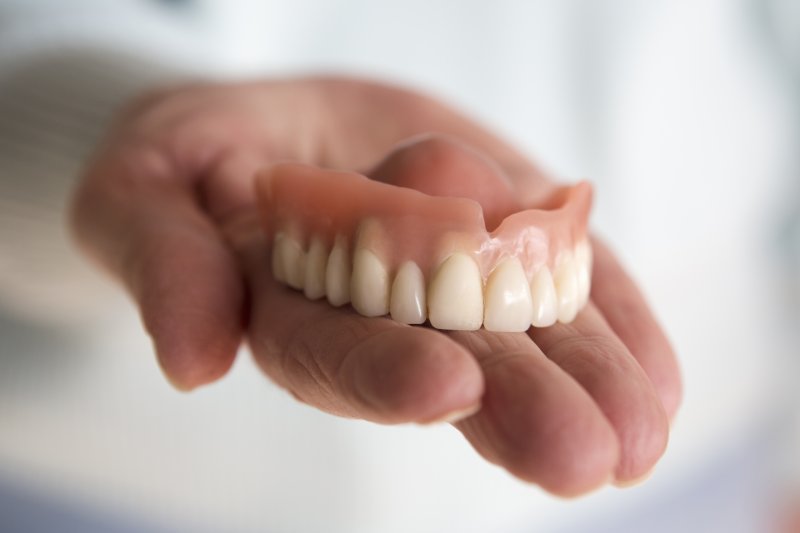 an upper denture sitting in a hand