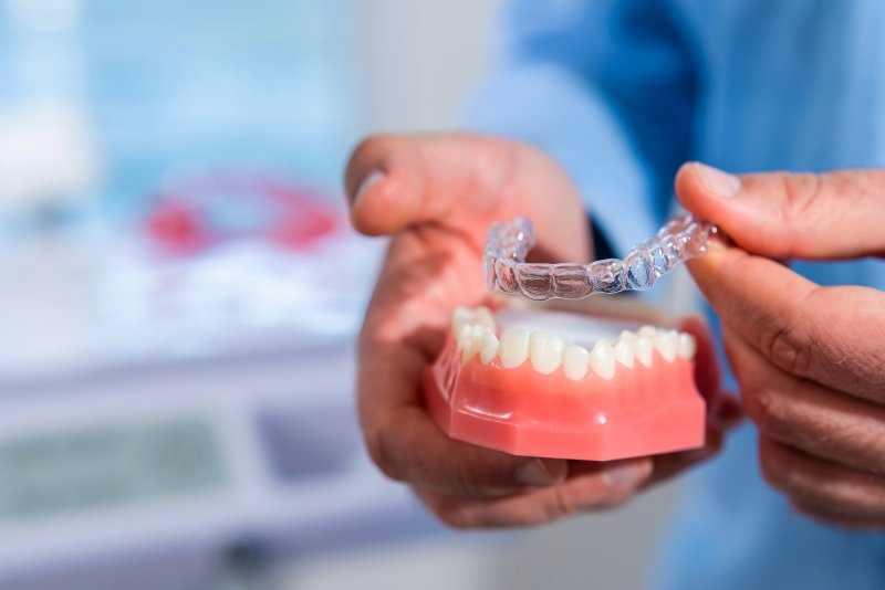 dentist holding a clear aligner and mouth mold