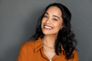 a woman in an orange blouse smiling happily